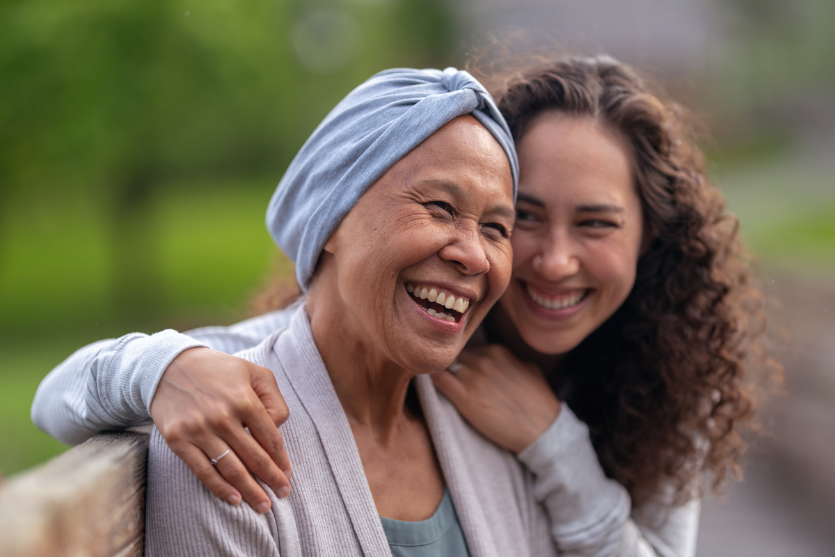 Happy senior woman with cancer laughing with daughter