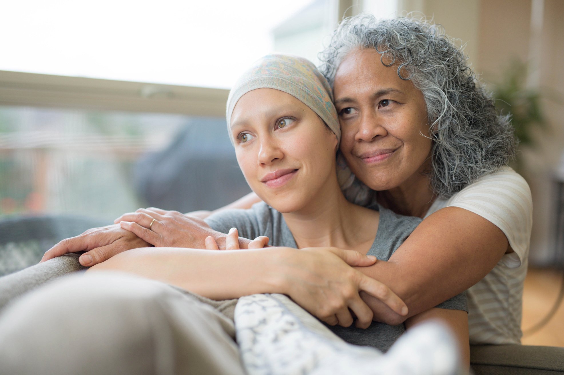 Ethnic young adult female cancer patient hugged by her mother