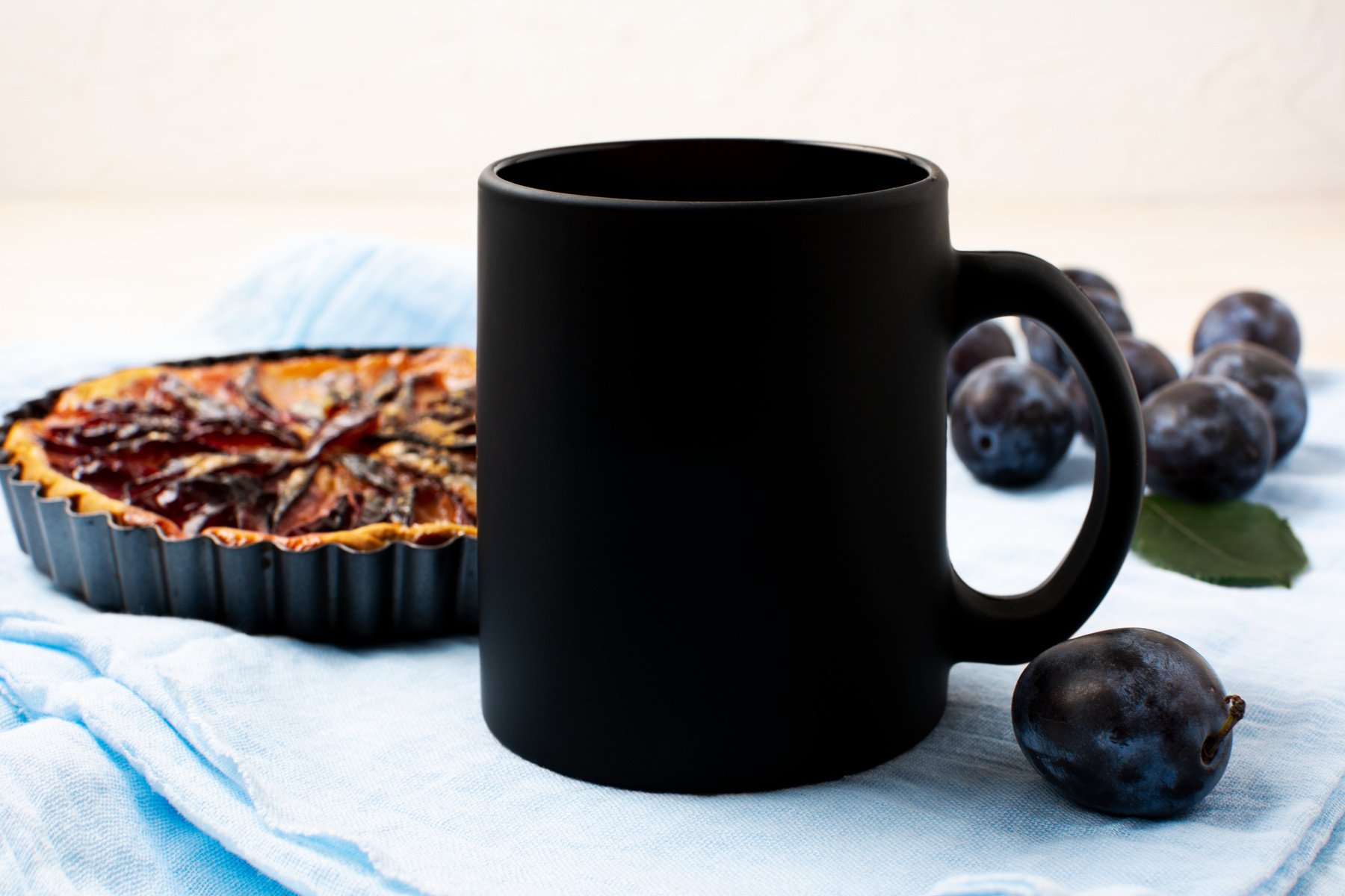 Black coffee mug mockup with plum pie